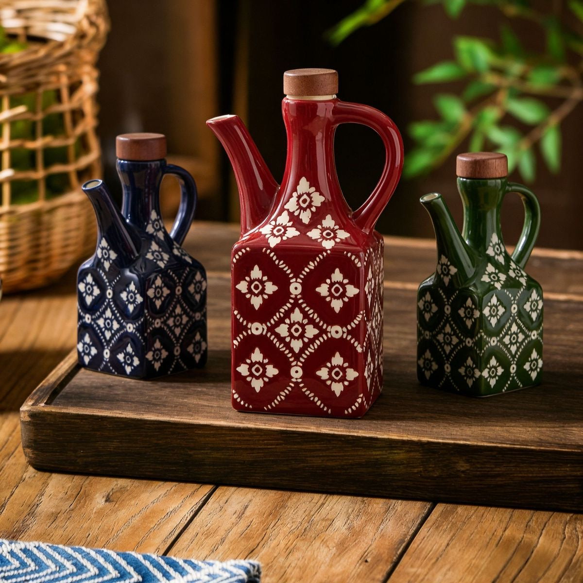 En lille blå, en stor rød og en lille grøn keramisk olivenolieflaske i pæne rammer