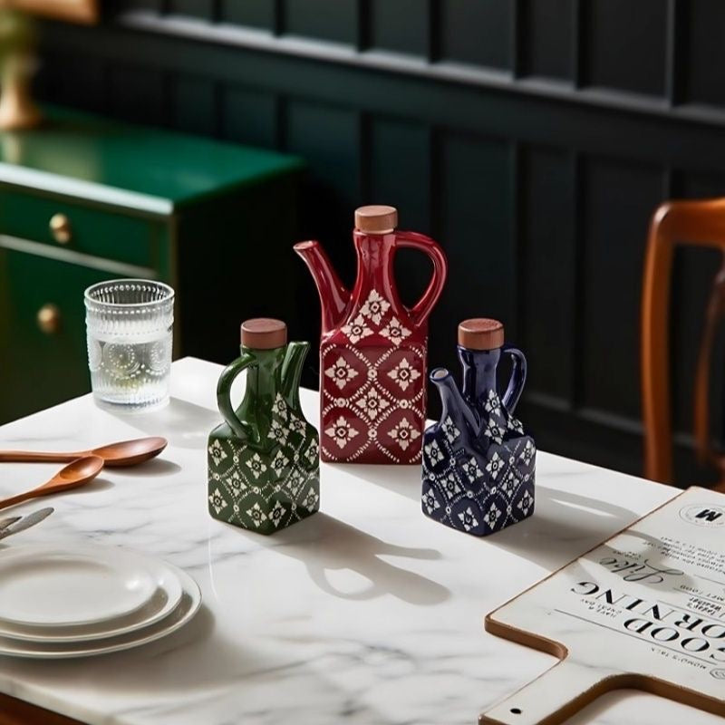 En stor rød, en lille grøn og en lille blå keramisk olivenolieflaske