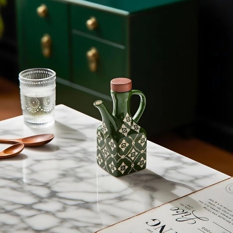 Lille grøn keramisk olivenolieflaske på et bord