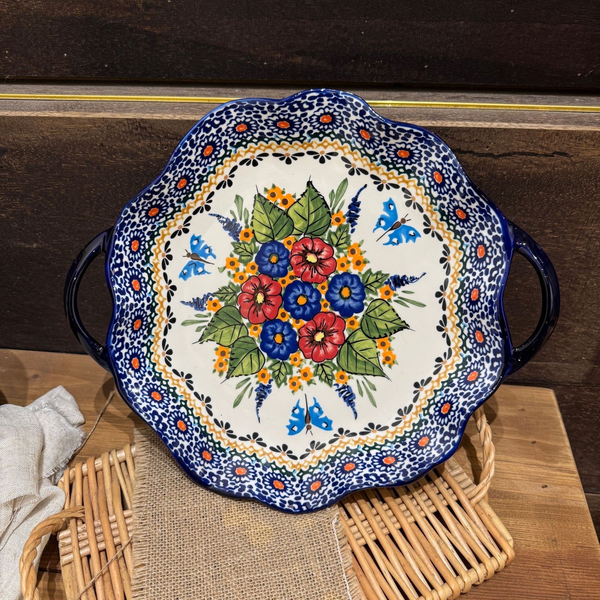 Dekorativt serveringsfad i keramik med bølget blå kant og praktiske håndtag