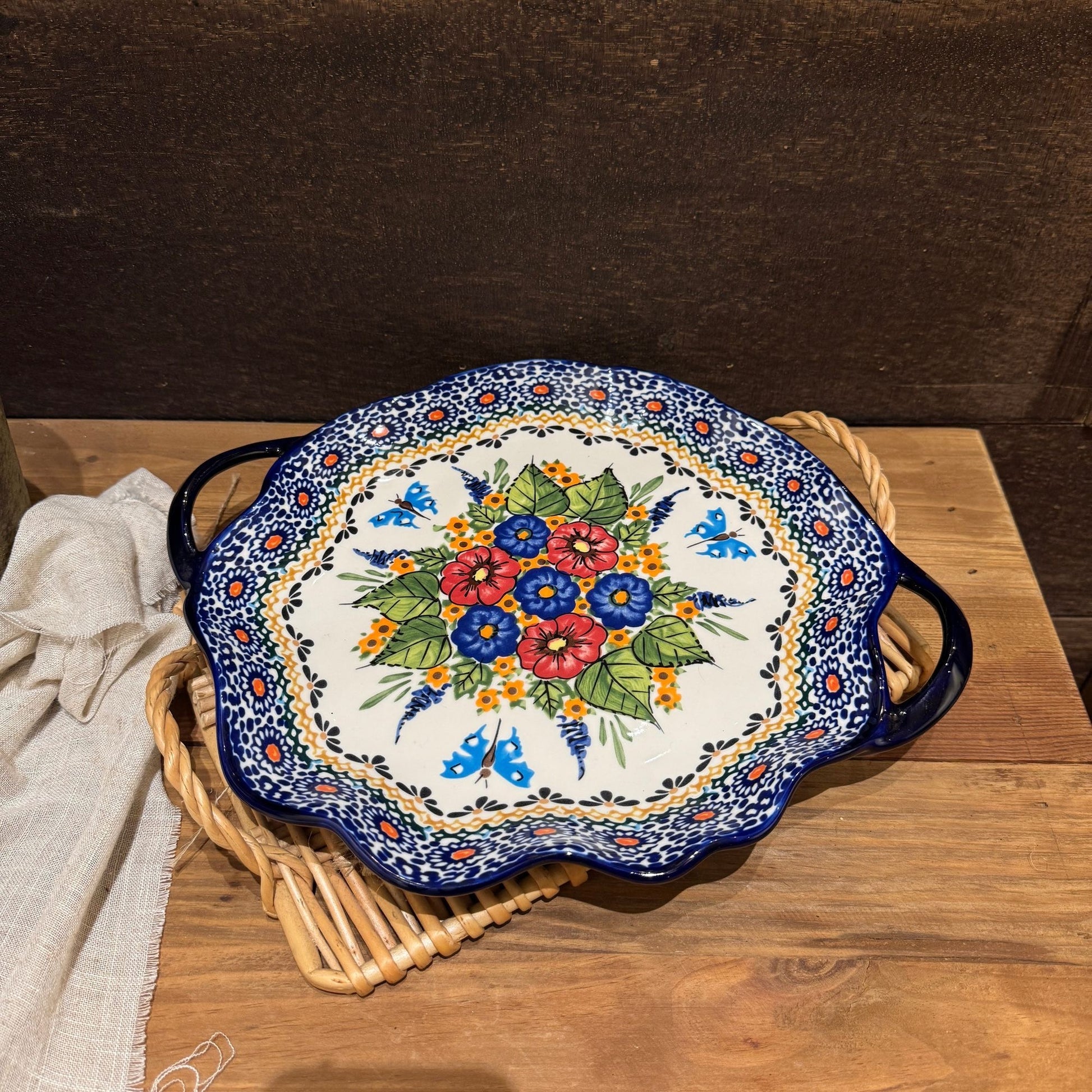 Rundt keramikfad med håndtag og farverigt blomstermotiv set oppefra på træbord